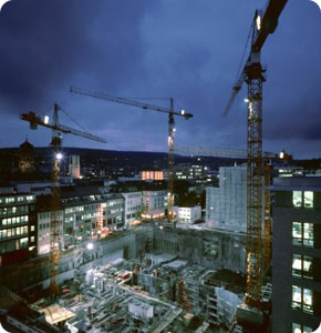 Nighttime construction site with cranes and building progress in the city.