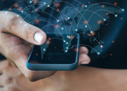 Hand holding smartphone with digital world map and network connections.