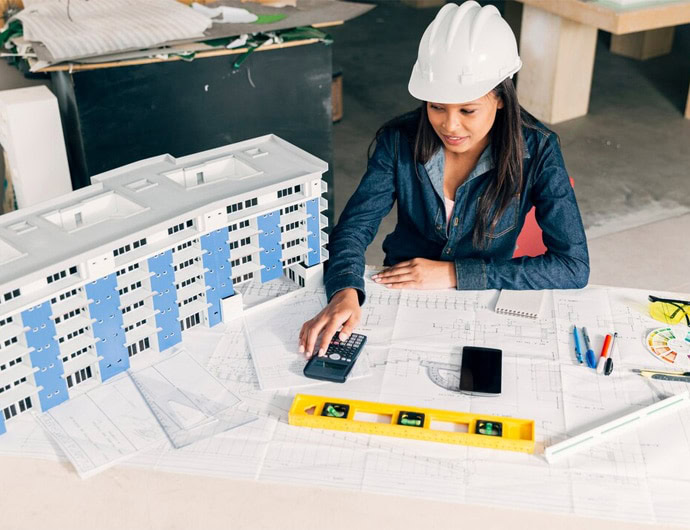 Female engineer with a hard hat reviewing construction blueprints and models.