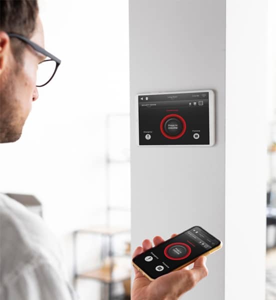 Person using smartphone to control smart home device on wall.